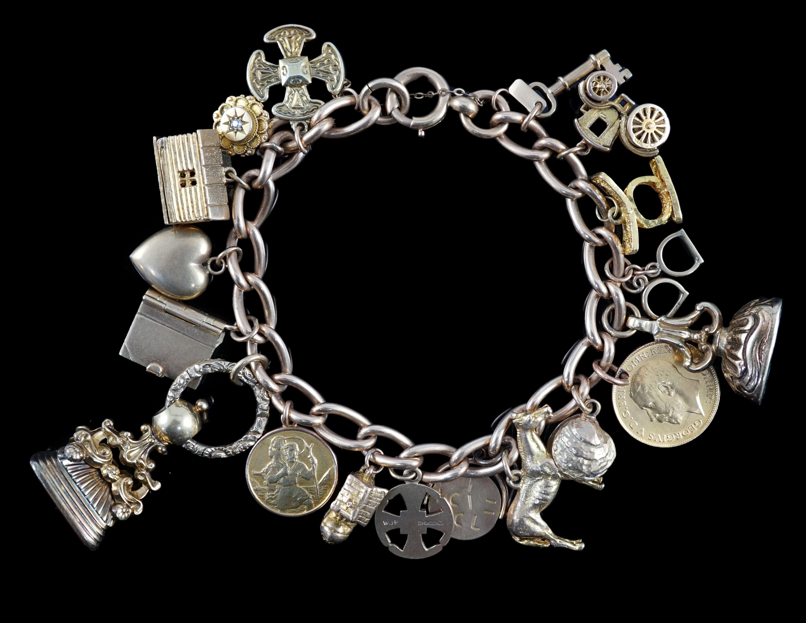 A 15ct? gold oval link charm bracelet, hung with seventeen assorted mainly 9ct charms